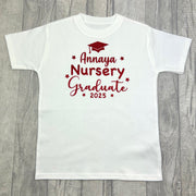 Children's white t-shirt featuring red stars and graduation cap design with lettering saying Personalised name Nursery Graduate 2025.